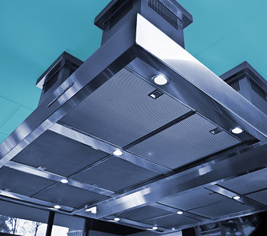 Close-up view of a stainless steel commercial kitchen exhaust hood with embedded lights in a modern kitchen.